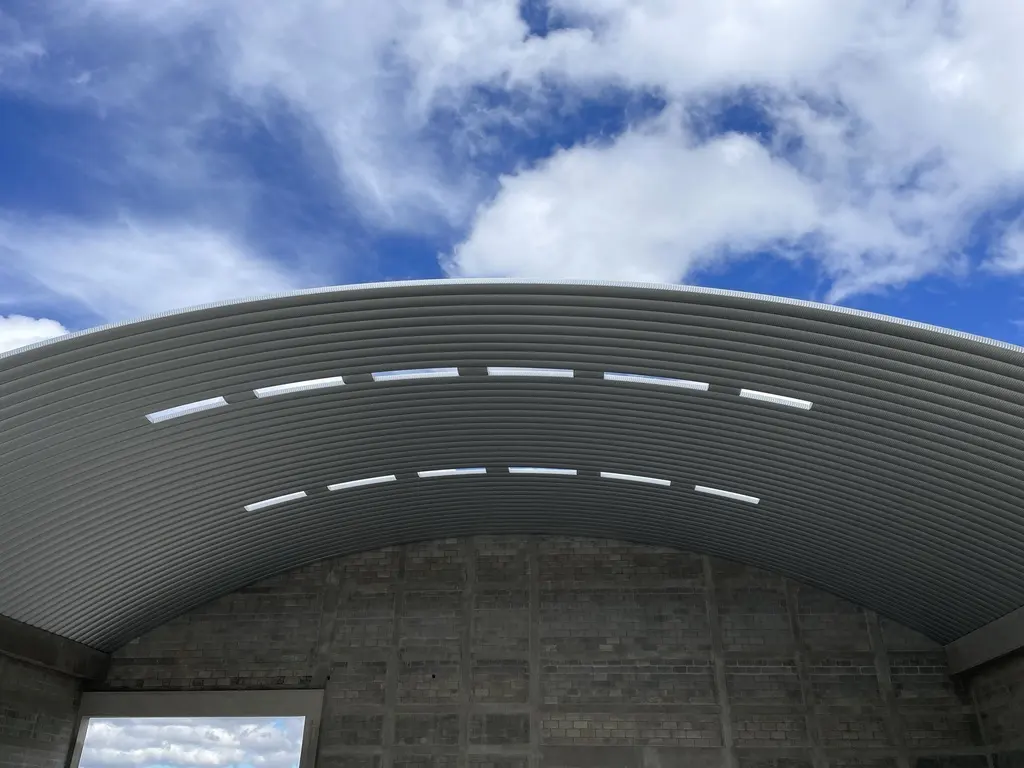 Curvatura de una cubierta metálica vista desde el interior contra el cielo azul